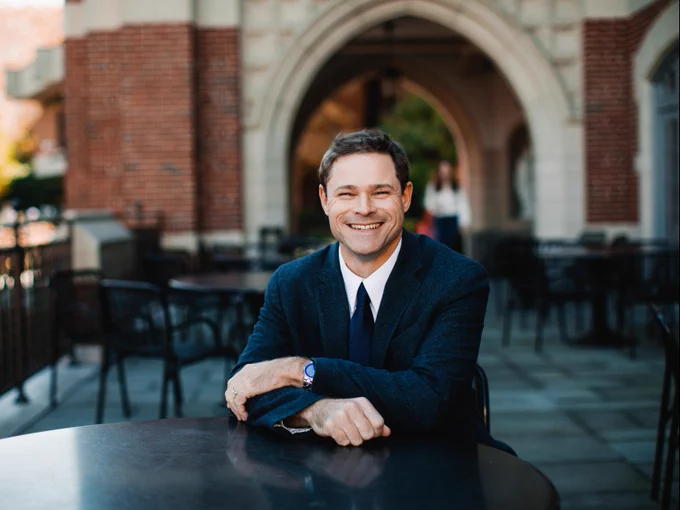Ted Andrews, Ph.D. '01 sits in front of Ruane Center for the Humanities.