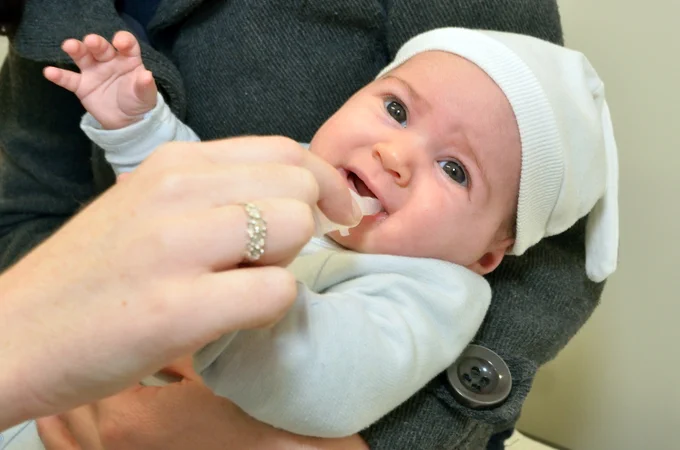 Infant in white receiving oral rotavirus vaccine