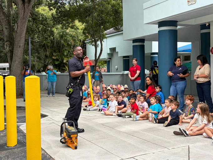 An MDFR Community Affairs member demonstrates an ax to a group of seated students.