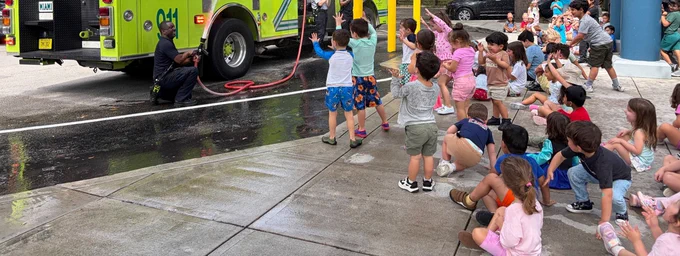 Miami-Dade Fire Rescue fire truck spraying water in front of a group of children.