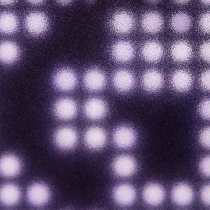 A close up photo of a Logitech G “G” logo created out of negative space, surrounded by small white circular LED bulbs. 