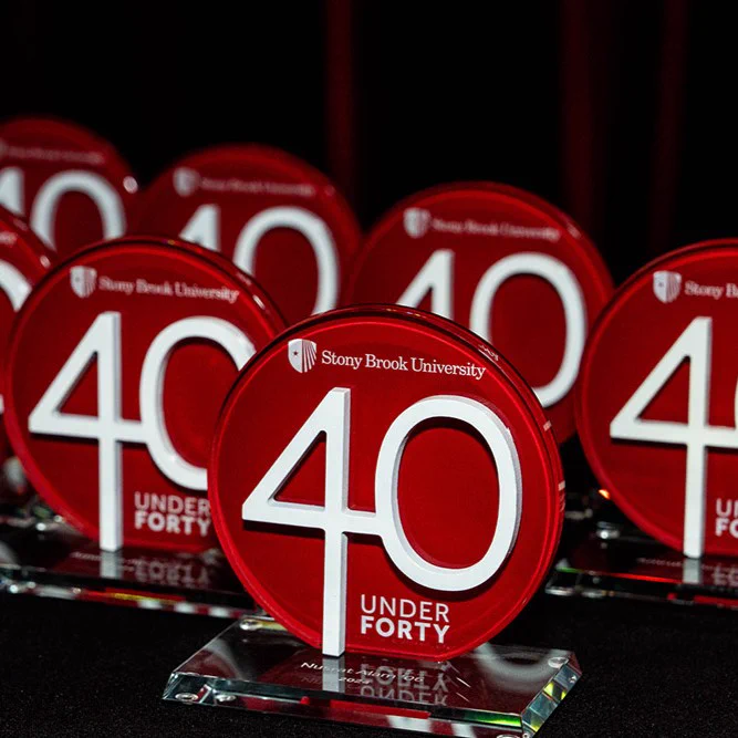 Awards with the Stony Brook University logo, labeled "40 Under Forty," displayed in a row on a black surface.