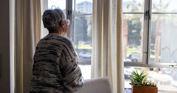 Elderly woman looking out a window.