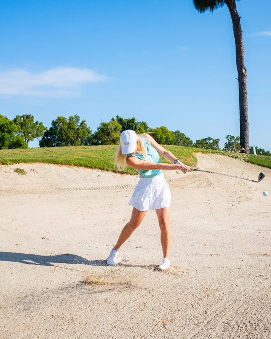 A photo of a woman golfing, hitting out of a bunker at Innisbrook Resort in Palm Harbor, FL.