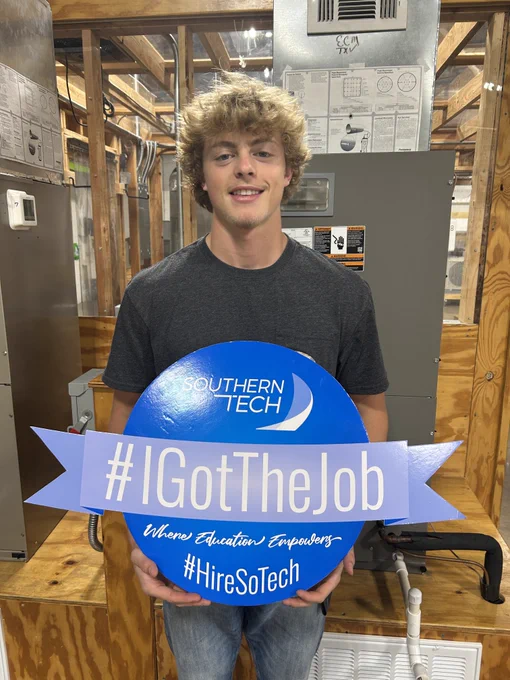 student holding an I got the job sign.