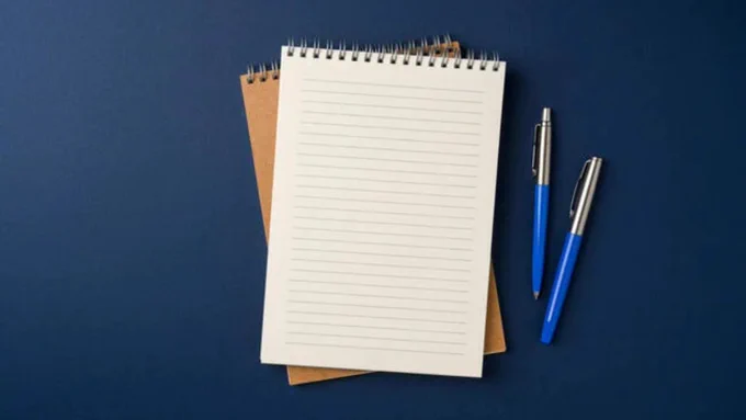 A spiral-bound notebook and two pens.