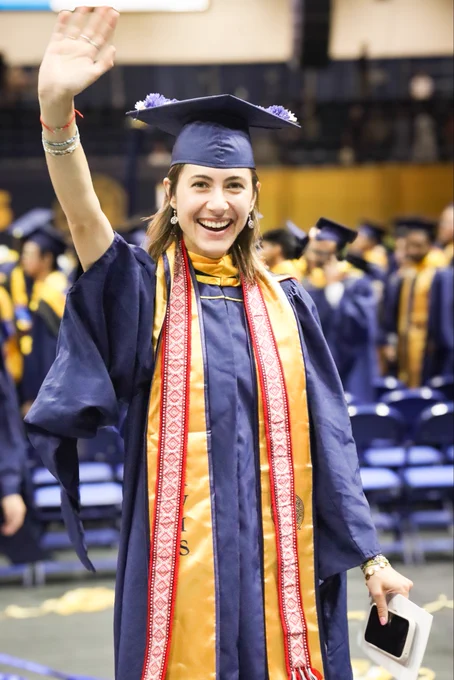 Master's graduate waving and smiling.