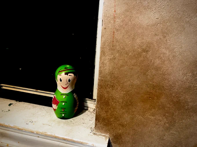 The Elf positioned on a window sill with an ominous black void out the window behind him. ✅