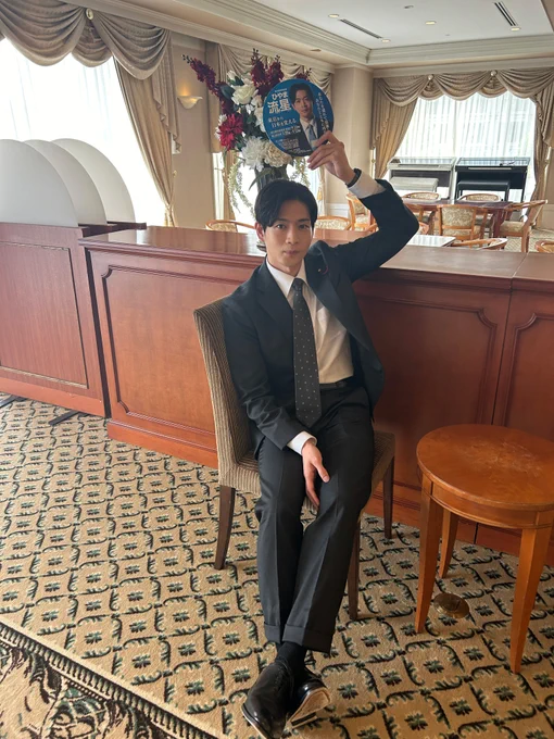 撮影のオフショット。
選挙ビラうちわを持ち、スーツ姿で椅子に座る
日山流星（ひやま・りゅうせい）役の松下洸平（まつした・こうへい）さん。