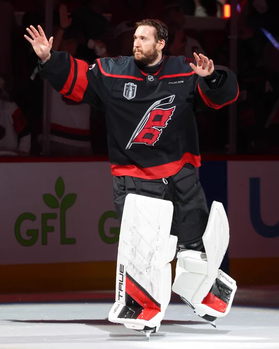 Brandon Bussi saluting the crowd on ice in a Hurricanes uniform.