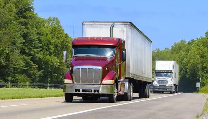 Large commercial trucks traveling on a Florida highway, illustrating truck safety awareness, defensive driving practices, and safe road-sharing techniques for motorists.