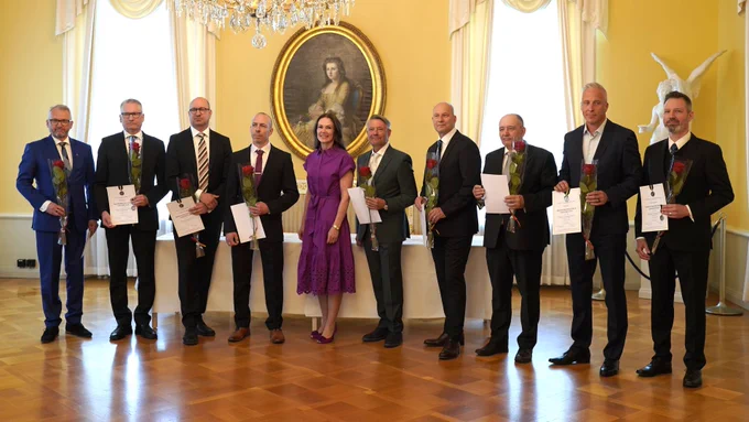 Liikenne- ja viestintäministeri Lulu Ranne ja mitalin saajat ruusut ja mitalit kädessä.