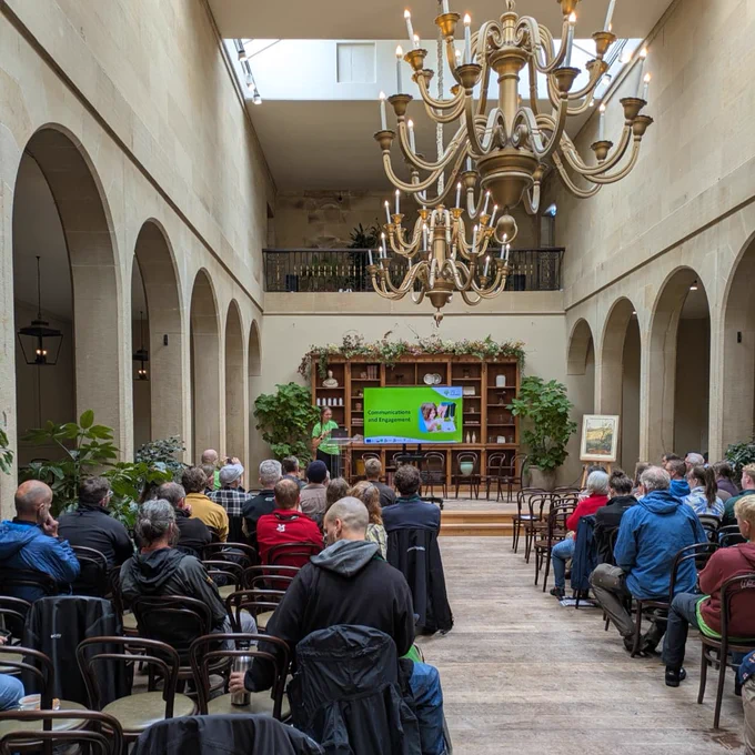 Conference room, with people watching a presentation on a screen at the front.