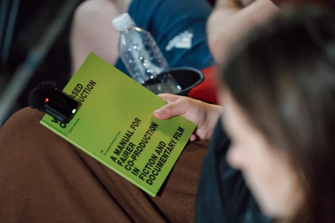 someone holding the value-based co-production manual in their lap with a clip mic attached to the manual.