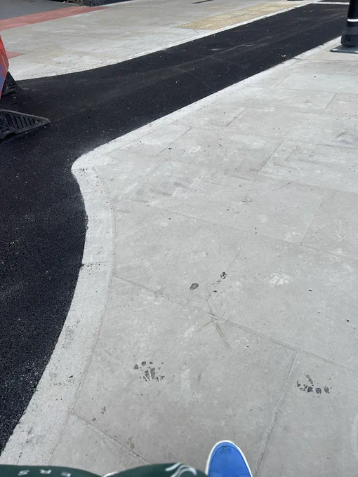 Stone flags on bus island completely level with black tarmac of cycle track without any form of kerb.