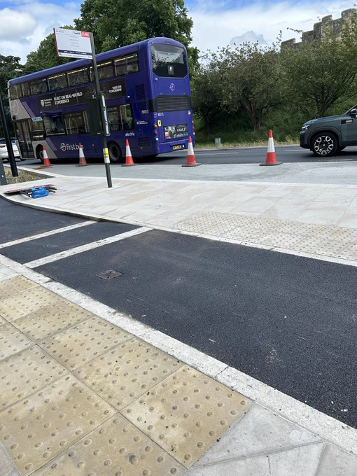 Buff colour tactile paving leading to bus island of floating bus stop near Milner hotel.