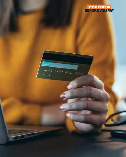 Person on laptop and hand holding bank card.
Stop Check Before you pay 