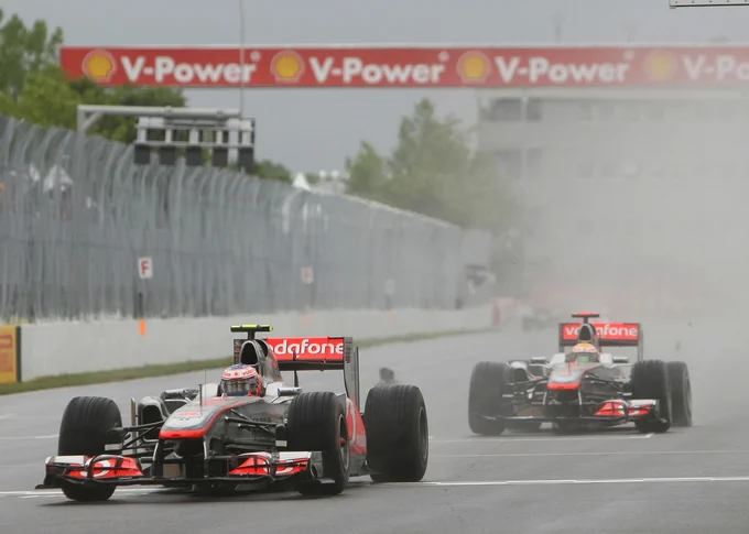 Spray and debris flying through the air, Jenson Button leads team-mate Lewis Hamilton, both in chrome and red McLaren MP4/26s after the two have collided. Hamilton's car is missing half its front wing and has a left rear puncture, while Button's appears undamaged. Andy Hone.