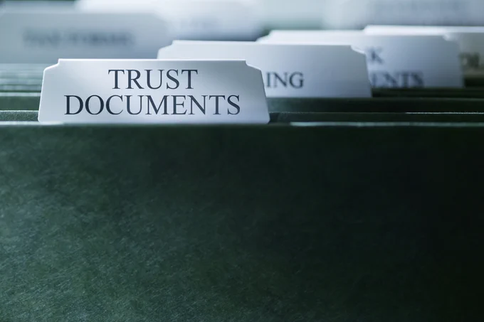 Close-up of a file folder labeled 'Trust Documents' among other organised folders in a filing system.