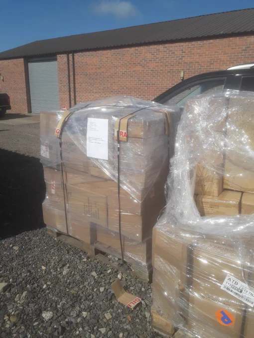 Several shrink-wrapped pallets of Trabasack stock sit outside a warehouse after delivery. The shipment arrived as part of the latest restock and includes stock allocated for the new Active Hands partnership.