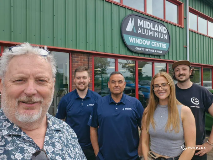 A group photo of five smiling people standing outside the Midland Aluminium Window Centre. The atmosphere is casual and friendly, and the team appears ready for a productive day.