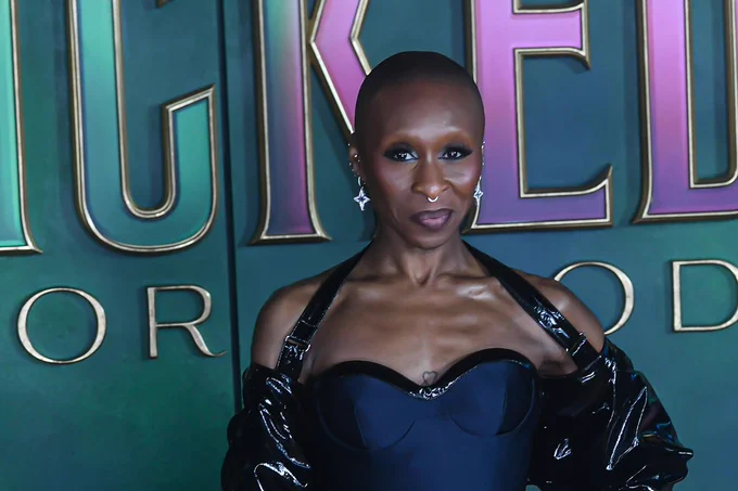 A photo showing a woman in front of a green step and repeat board 