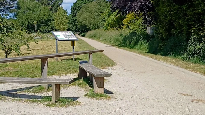 Photo shows a gravel path on the Camel Trail with trees and a signpost.