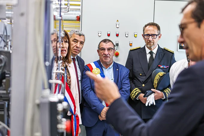 Le ministre posant des questions sur une installation industrielle. Les élus et le préfet le regarde.