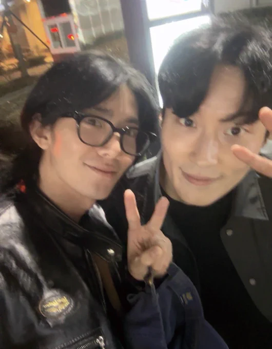 Hwiyoung selca with Heo Namjun. They are both wearing black, Hwiyoung is also wearing black glasses.
Both are holding up one hand doing a V sign & look absolutely adorable and super handsome.