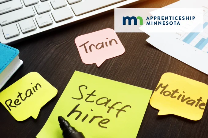 A desk with notes that read retain, train, motivate and staff hire.