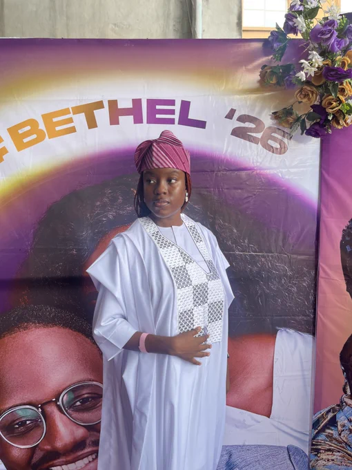 In this photograph, MaryRose is wearing a white Agbada neatly embroidered, and a peach Aso-Oke cap.
She is standing with her head turned to the side, one arm across her body and a slight smile on her lips.
As always, she looks gorgeous.