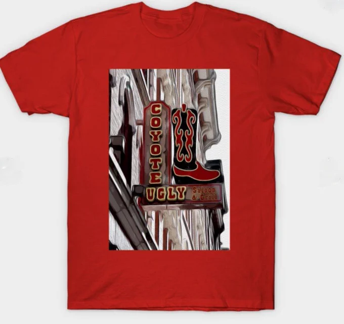 Vertical sign on a building for the entrance to Coyote Ugly Saloon and Grill in Nashville Tennessee. The sign is in an L shape with COYOTE going down and UGLY going across horizontally.  It appears to be sitting or placed on the horizontal section of the L is a red and black cowboy boot.  Photo Art by Debra Martz
Image printed on a Red T-shirt