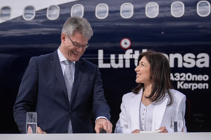 Auf dem Bild sieht man links Bundesverkehrsminister Patrick Schnieder und rechts Bundeswirtschaftsministerin Katherina Reiche, die auf der ILA 2026 in Berlin zusammen vor einem Flugzeug der Lufthansa an einem Pult stehen.