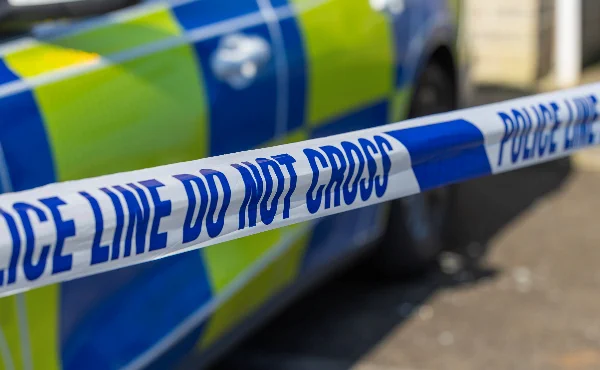 Close-up of a police tape in front of a patrol car.