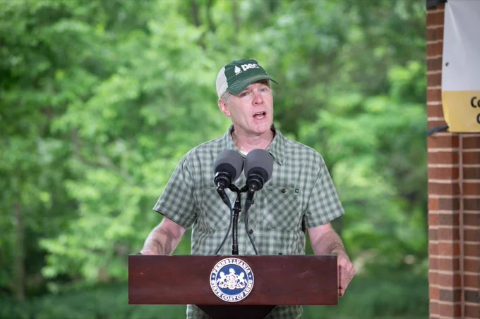 PEC President, Tom Gilbert speaking at a podium outside. 