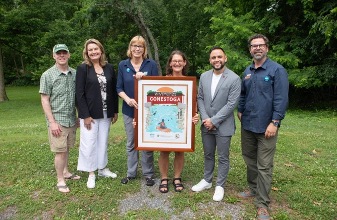 PEC President, PA DCNR Secretary and three other individuals standing around the 2026 River of the Year poster. 