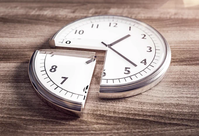 A clock lying on a table with a quarter of it cut out like a slice of cake