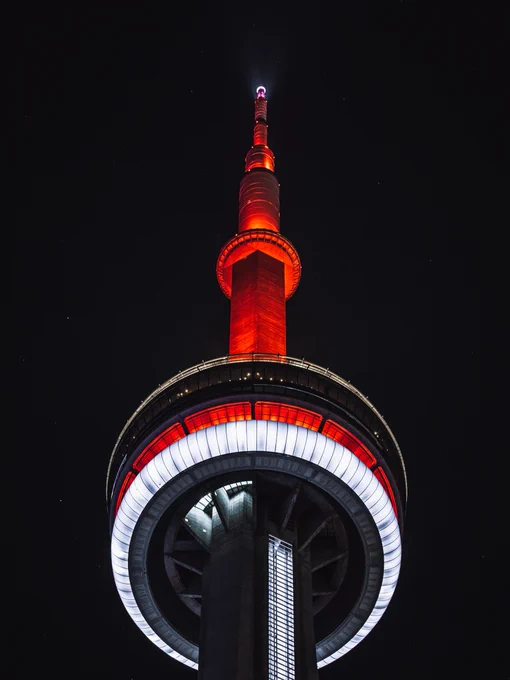 Closeup of the CN Tower at night lit red and white / Gros plan de la Tour CN illuminée en rouge et blanc la nuit 