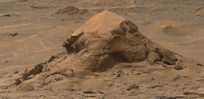 A rust toned image capturing the Mira Flores butte, a small erosional outlier standing alone in the valley currently explored by the Mars rover Curiosity on its way to the Yardang Unit.