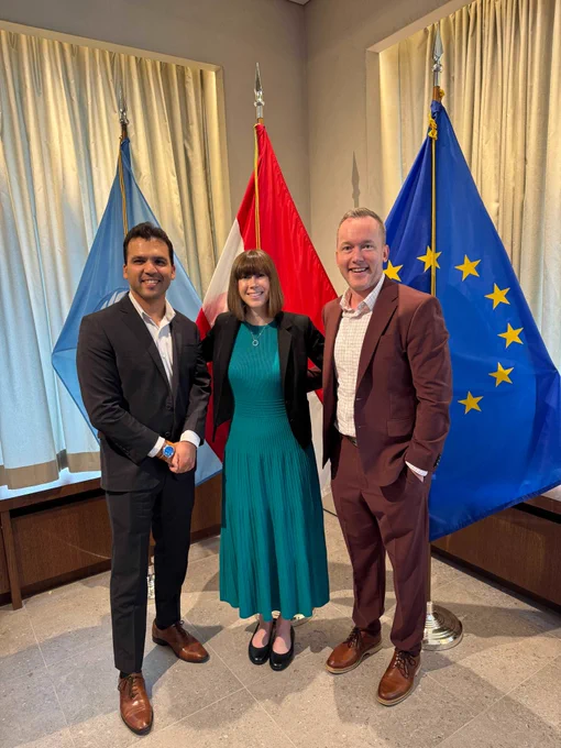 Varun Chandak (left) poses with two attendees at a side event during the Conference of States Parties (COSP) at the United Nations. The three individuals stand in front of United Nations, Austrian, and European Union flags in a meeting room at the Austrian Permanent Mission to the United Nations. 