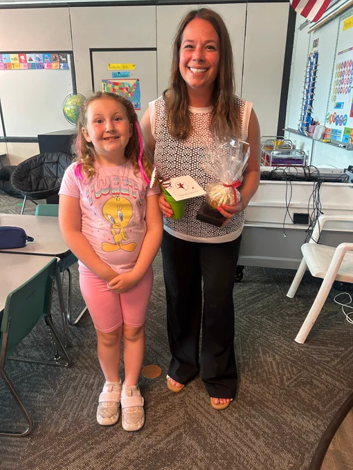 Teacher and student in classroom with thank you gifts in hand.