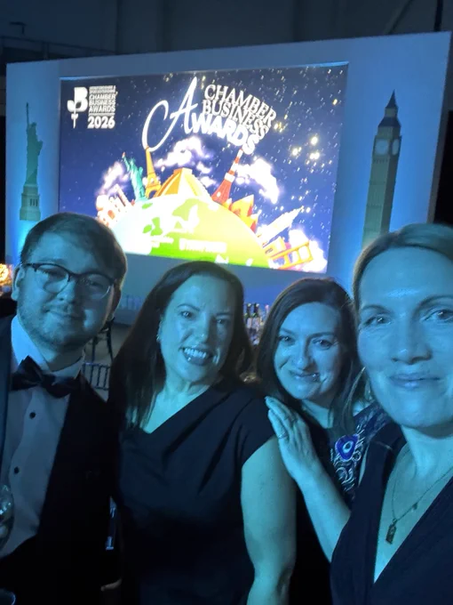 4 members of the Dolphin team in front of the screen displaying the Chamber Business Awards artwork