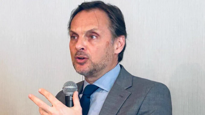 Primer plano de Stefano Pettinato, representante residente del PNUD en Uruguay, durante su intervención. Sostiene un micrófono mientras expone ante la audiencia.
