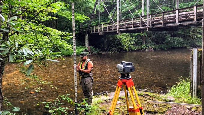 A USGS hydrologic technician holds the level rod during an annual set of levels at the historic Cataloochee Creek near Cataloochee, North Carolina. Photo by Jessica Moore, USGS