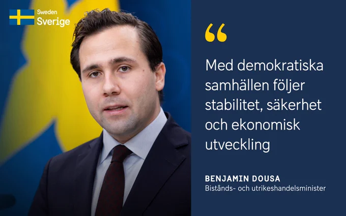 Porträtt av Benjamin Dousa, bistånds- och utrikeshandelsminister, med citatet: "Med demokratiska samhällen följer stabilitet, säkerhet och ekonomisk utveckling".