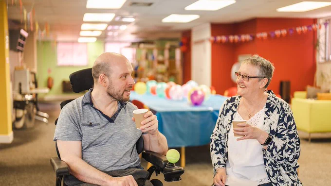 Two older people sit in a carehome together and chat