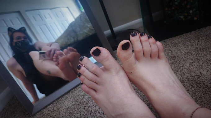 a picture of my feet, my toenails are painted black. you can see a reflection of me sitting on the floor in a mirror