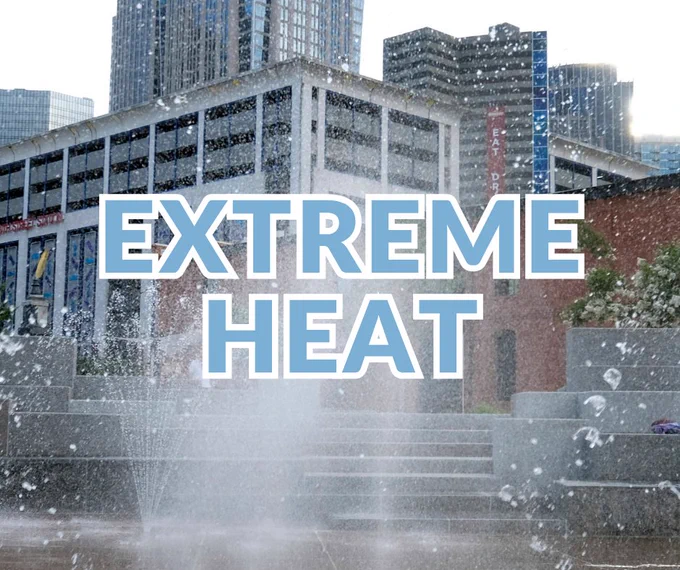 Scene at a sprayground with splashing water with a city background with modern buildings. Large text in the center reads "Extreme Heat".