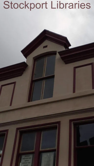 Building facade with windows and decorative trim under a grey sky.