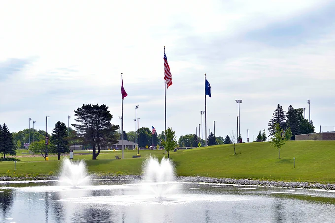 U.S. flag display on Central Campus, with pond and fountain in foreground. 